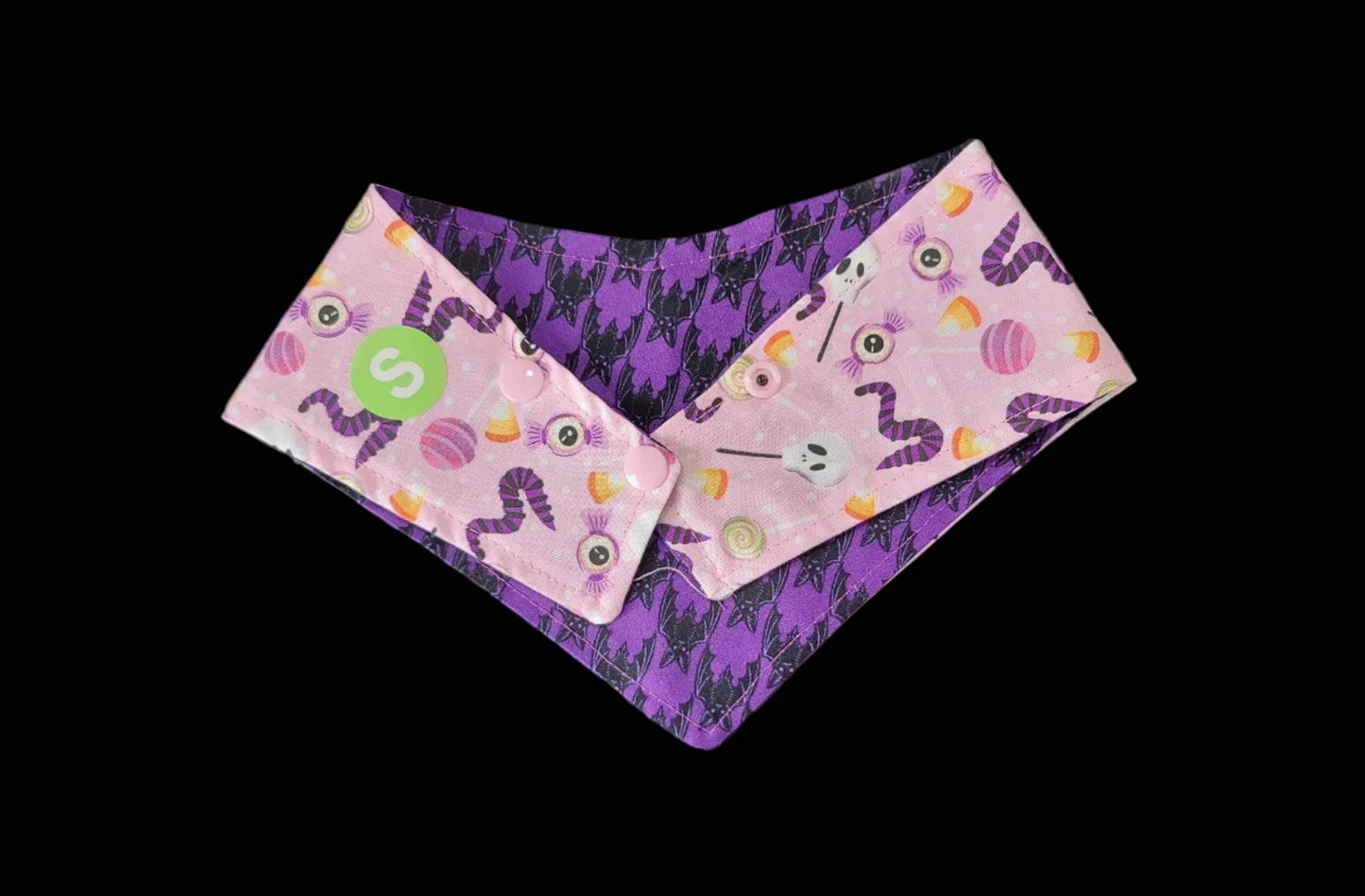Halloween-themed bandanas with purple and pink designs on a dark surface.