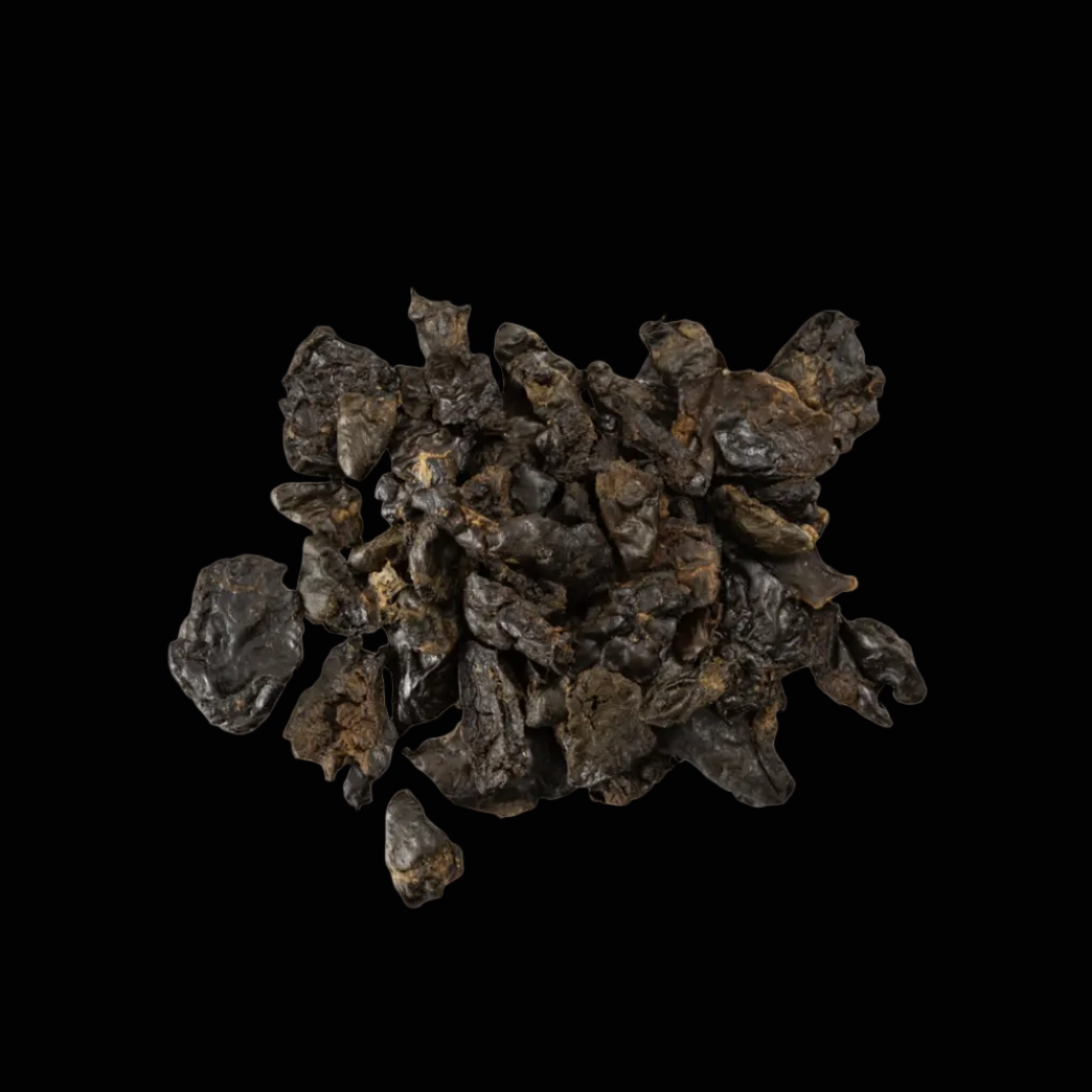 Pile of dark brown dried chicken hearts on black background
