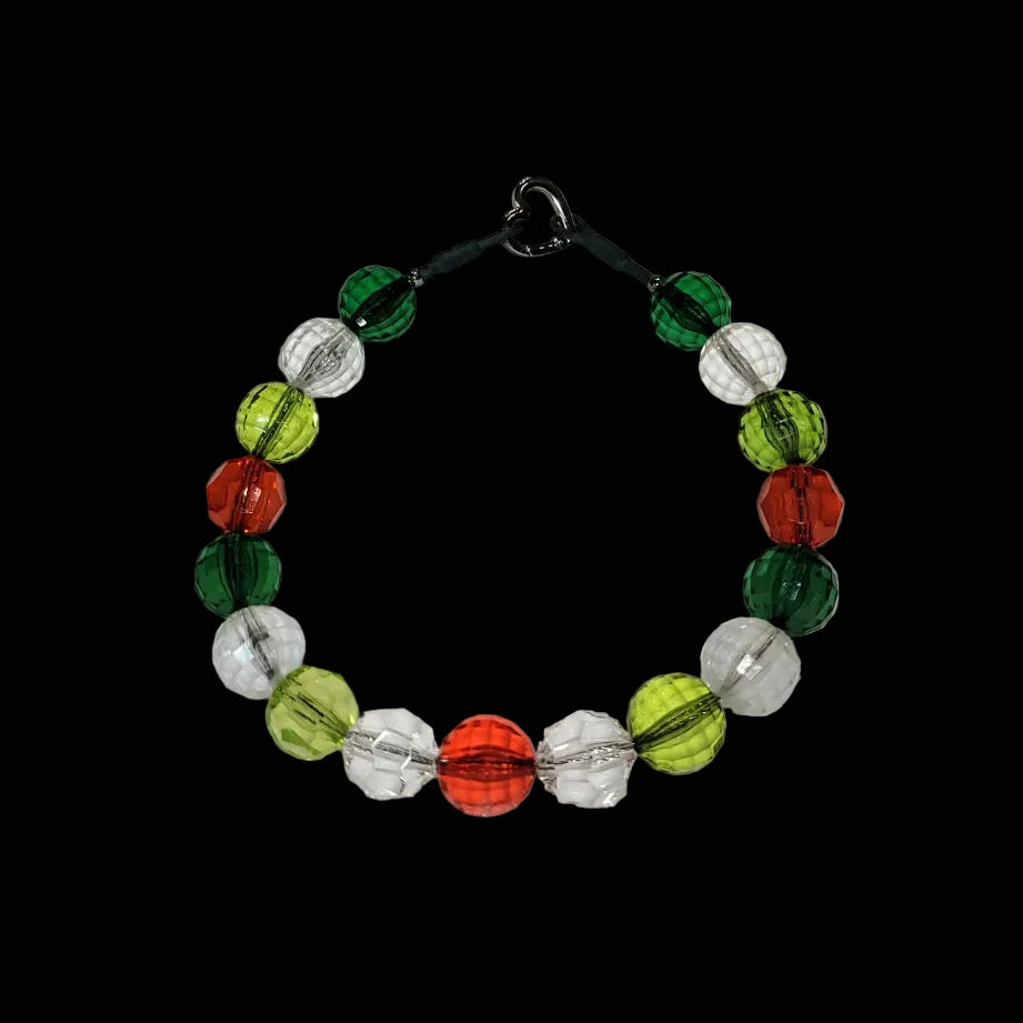 Beaded bracelet with green, red, and clear beads on a wooden surface