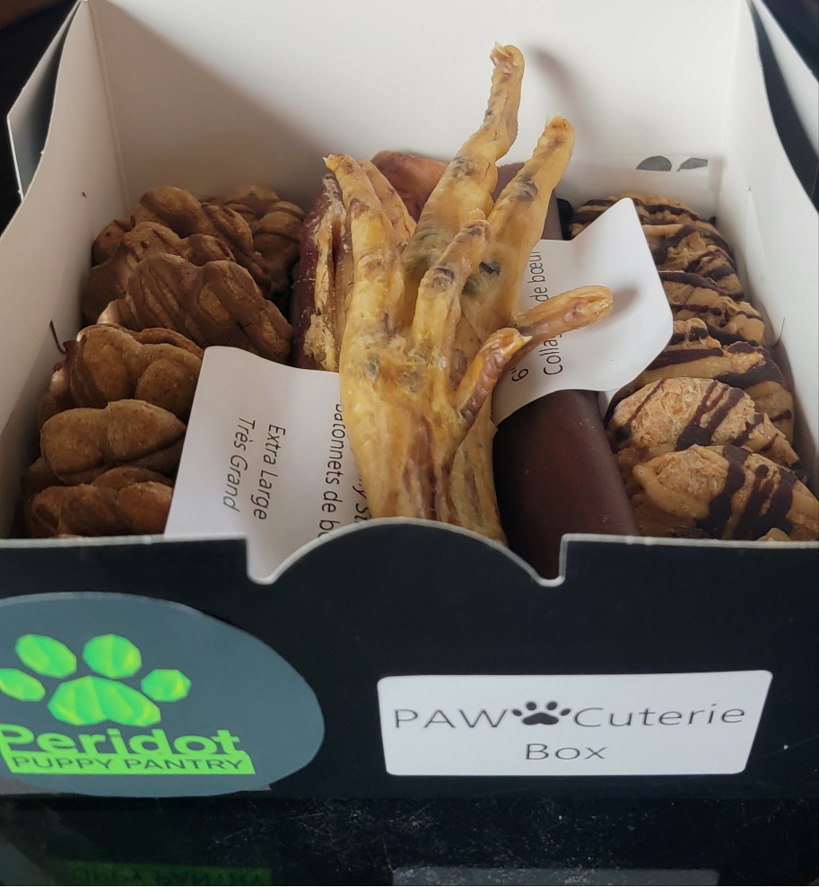 Box of dog treats with 'Peridot Puppy Pantry' and 'PAW Cuterie' branding.