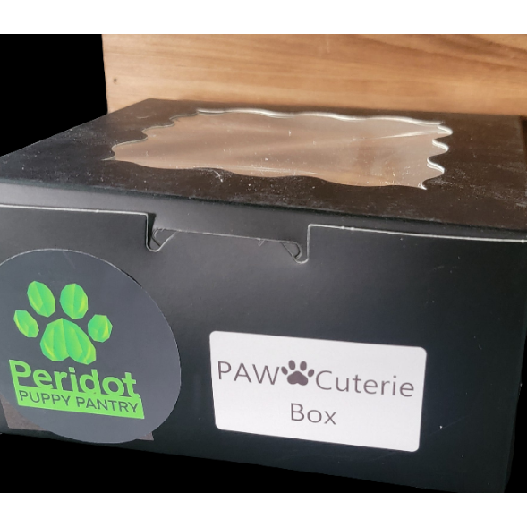 Black box with Peridot Puppy Pantry and PAW Cuterie Box labels on a wooden surface.