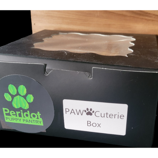 Black box with Peridot Puppy Pantry and PAW Cuterie Box labels on a wooden surface.