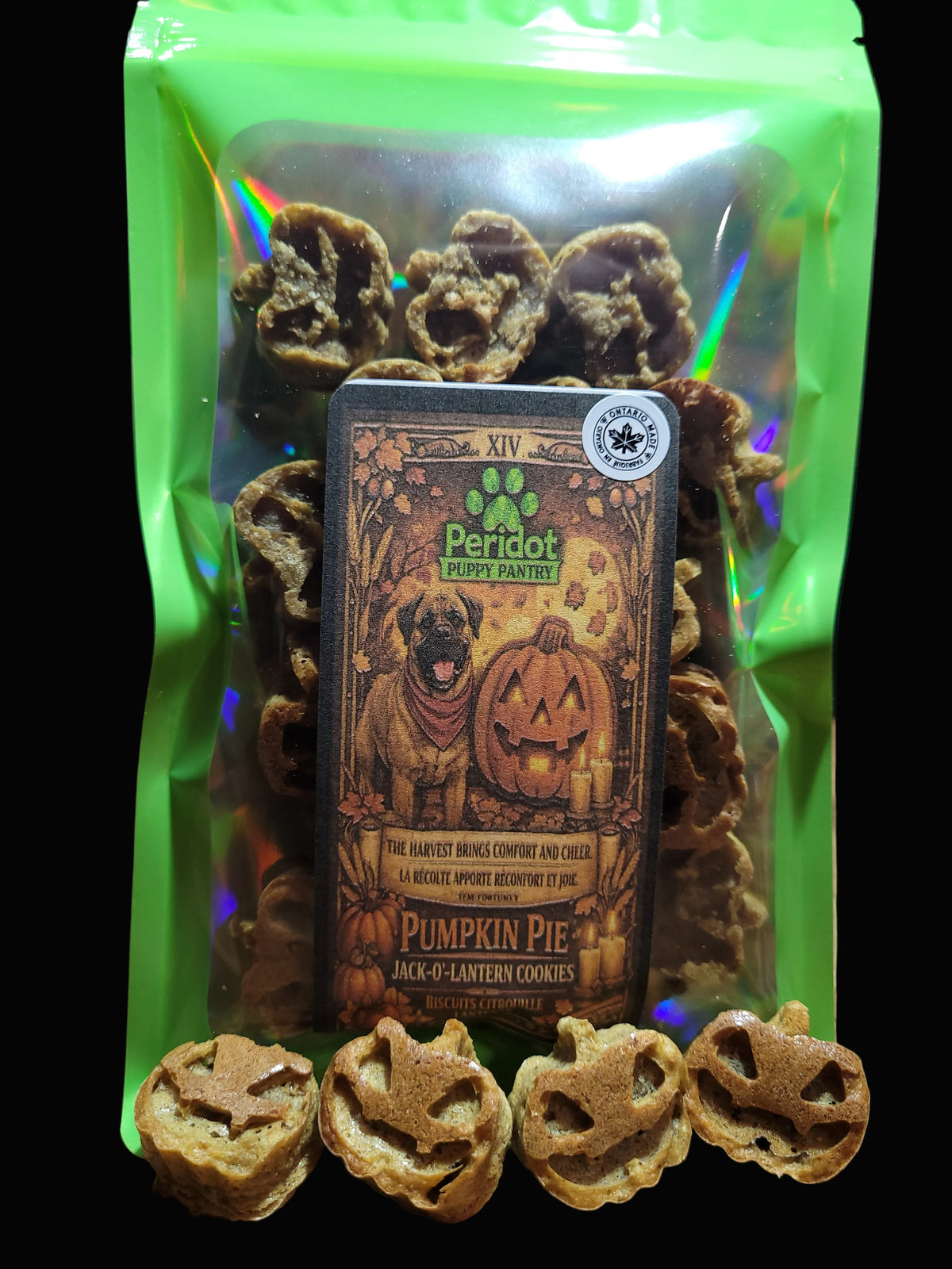 A green resealable bag of Peridot Puppy Treats Halloween Pumpkin Pie Jack-o'-lantern cookies, with four small pumpkin-shaped dog treats